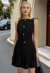 Detail of a black sleeveless dress showing golden embossed buttons and pleated waistline
