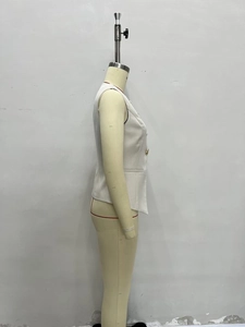 Detail of white sleeveless vest featuring decorative gold buttons and tailored lapels
