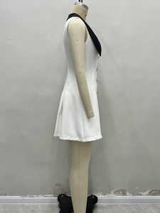 Détail de robe blanche sans manches avec revers noir contrasté et boutons dorés