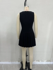 Detail view of the back of a black sleeveless dress featuring a pleated hem and a zipper
