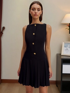 Detail of elegant black sleeveless mini dress featuring gold buttons and pleated skirt
