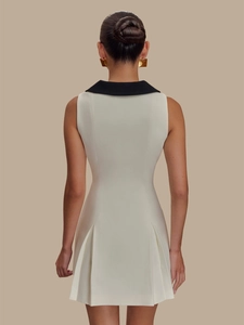 Robe blanche sans manches élégante avec col à revers noir et ourlet plissé cintré