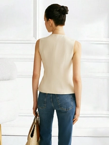 Chic beige sleeveless vest with back waist seam detailing and blue denim jeans