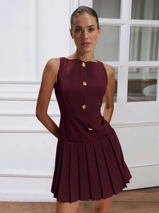 Detail of burgundy sleeveless pleated dress featuring artistic gold buttons and chic round neck