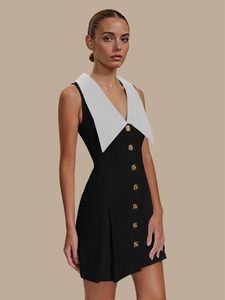Détails du revers blanc et des boutons dorés en relief sur une robe noire sans manches
