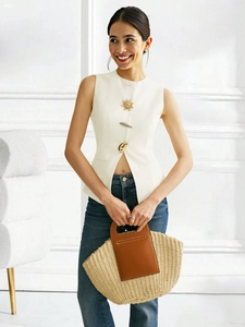Detail of white sleeveless vest top with gold decorative buttons and straw handbag
