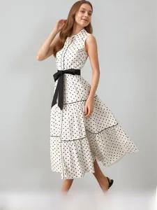 Dettaglio dell'abito bianco a pois con fiocco nero in vita e colletto a camicia