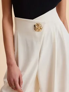 Detail of high waist trousers featuring asymmetric overlap and hammered gold button