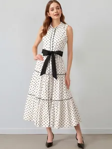 Elegante abito bianco a pois senza maniche con fiocco nero in vita e gonna a balze