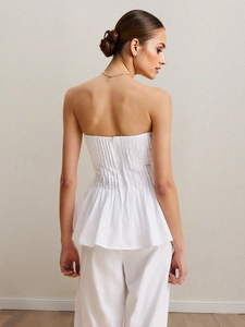 Ensemble chic blanc avec haut épaules dénudées et pantalon avec détails plissés