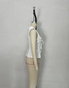 Detail of white sleeveless blouse featuring a sharp collar and double bow tie design