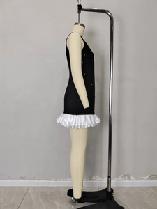Side view of black sleeveless dress featuring white ruffles and pearl detail on mannequin