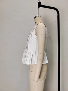 Detail view of white sleeveless pleated top showing vertical texture and A-line silhouette