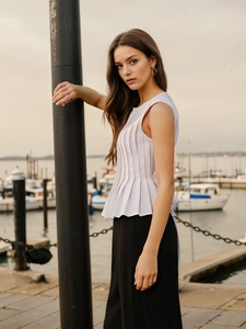 Close-up of a sleeveless lavender pleated top with a ruffled hem and textured details