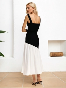 Elegant sleeveless black and white color block dress with a pleated hem in a minimalist setting