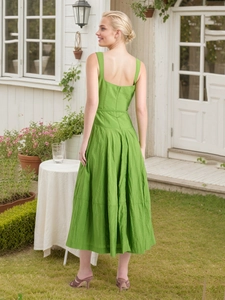 Elegante abito midi verde con scollo quadrato senza maniche per donna in un giardino