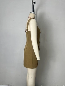 Detail of tan sleeveless dress showing wide straps and gold buttons on textured fabric