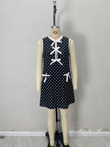 Elegant sleeveless black polka dot mini dress with white bow accents and round neck