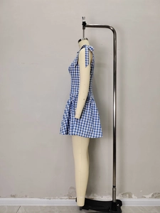 Detail of blue and white gingham dress showing shoulder bow ties and pleated hemline