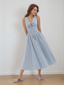Detail of light blue V-neck midi dress featuring chic double bow ties and pleated skirt