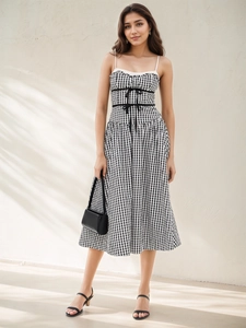 Détail de la robe vichy avec décolleté en dentelle blanche et nœuds noirs à la taille