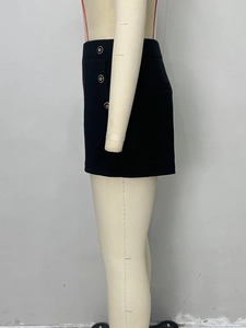 Gros plan sur trois boutons dorés décoratifs sur le short noir à taille haute