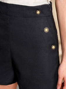 Détail du short noir à taille haute avec des boutons dorés de style héraldique