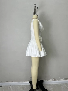 Detail of white satin dress featuring waist-defining 3D rose and pleated umbrella skirt