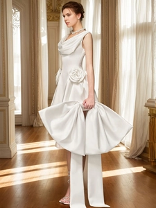 Detail of white satin dress featuring 3D floral waist accents and a large designer bow