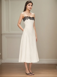 Dettaglio di abito estivo bianco sporco con pizzo nero e silhouette a trapezio elegante