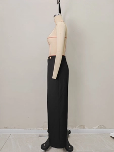 Detail of high waist black trousers featuring elegant side gold buttons and draped fabric