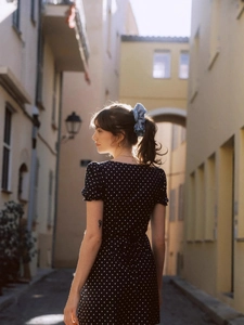 Détail d'une mini-robe rétro à pois bleu marine avec chouchou assorti