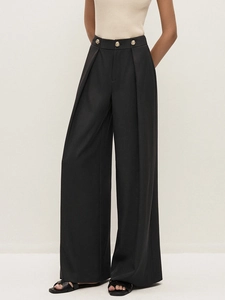Close-up of high-waisted black wide-leg trousers featuring golden buttons and pleated details