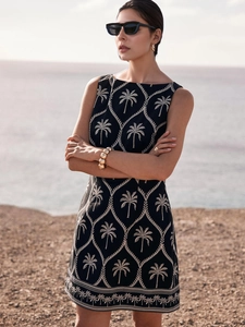 Elegantes ärmelloses schwarzes Kleid mit weißen Palmenstickereien und Küstenhintergrund