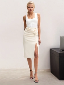 Detail of high-waist beige midi skirt with gold buttons, knot decor, and side slit