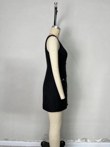Side view detail of a black tweed sleeveless dress with decorative buttons and front pockets