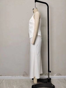 Detail of white minimalist two-piece set featuring side-slit vest and high-waisted maxi skirt