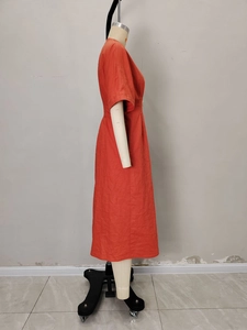 Dettaglio dello scollo a V e della trama del tessuto arancione sul vestito lungo
