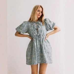 Detail of puff sleeves and front bow tie closures on blue floral denim mini dress