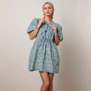 Detail of light blue floral jacquard denim dress with puff sleeves and bow tie neckline