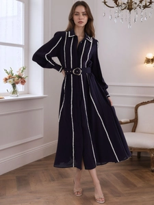 Detail of navy blue button-down midi dress with white vertical polka dots and gold buckle