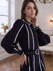 Detail of dark blue shirt dress featuring white polka dot trim and gold buckle belt