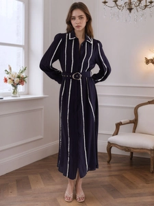 Detailed view of deep blue shirt dress featuring white trim accents and gold buckle belt