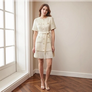 Detail of tweed dress showing gold buttons and white pleated hemline detail