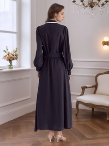 Detail of beaded cuff and waist-tie on a long-sleeved dark shirt dress with pearl accents
