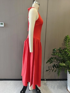Detail of red halter neck dress featuring a back-neck tie design and elegant pleated waist