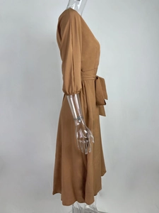 Detail van camel lange mouwen jurk met elegante taille strik en gladde textuur van stof