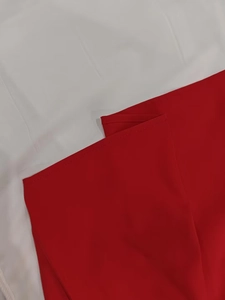 Macro shot of red dress fabric featuring precise stitching on a high-quality textured edge