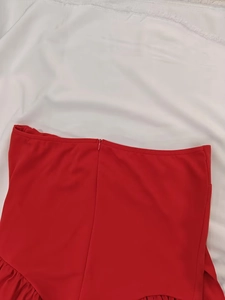 Detail view of the high waist red dress featuring a neat hidden zipper and pleated fabric