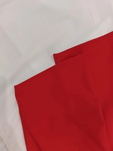 Detailed close-up showing the precise stitching and hem of the red V-neck dress fabric